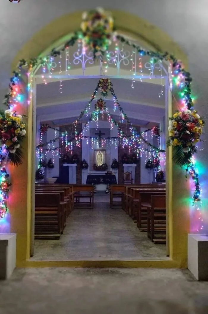 Entrada de la capilla adornada con luces y flores para la fiesta