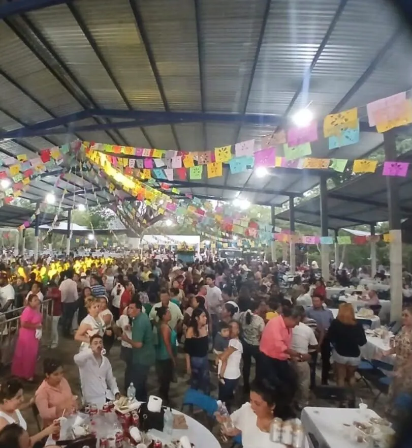 Comunidad conviviendo bajo el techado, con papel picado colgado