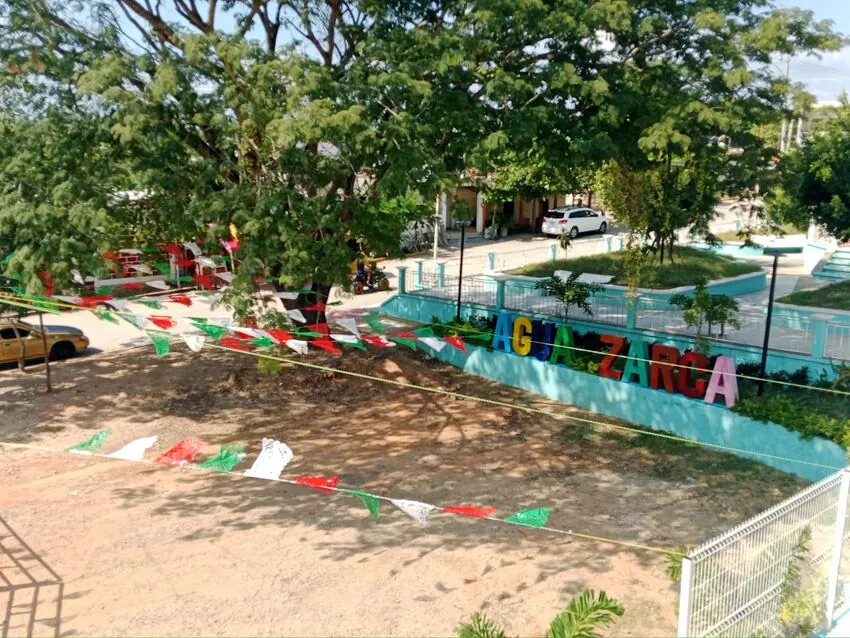 Letrero de Agua Zarca adornado con papel picado tricolor
